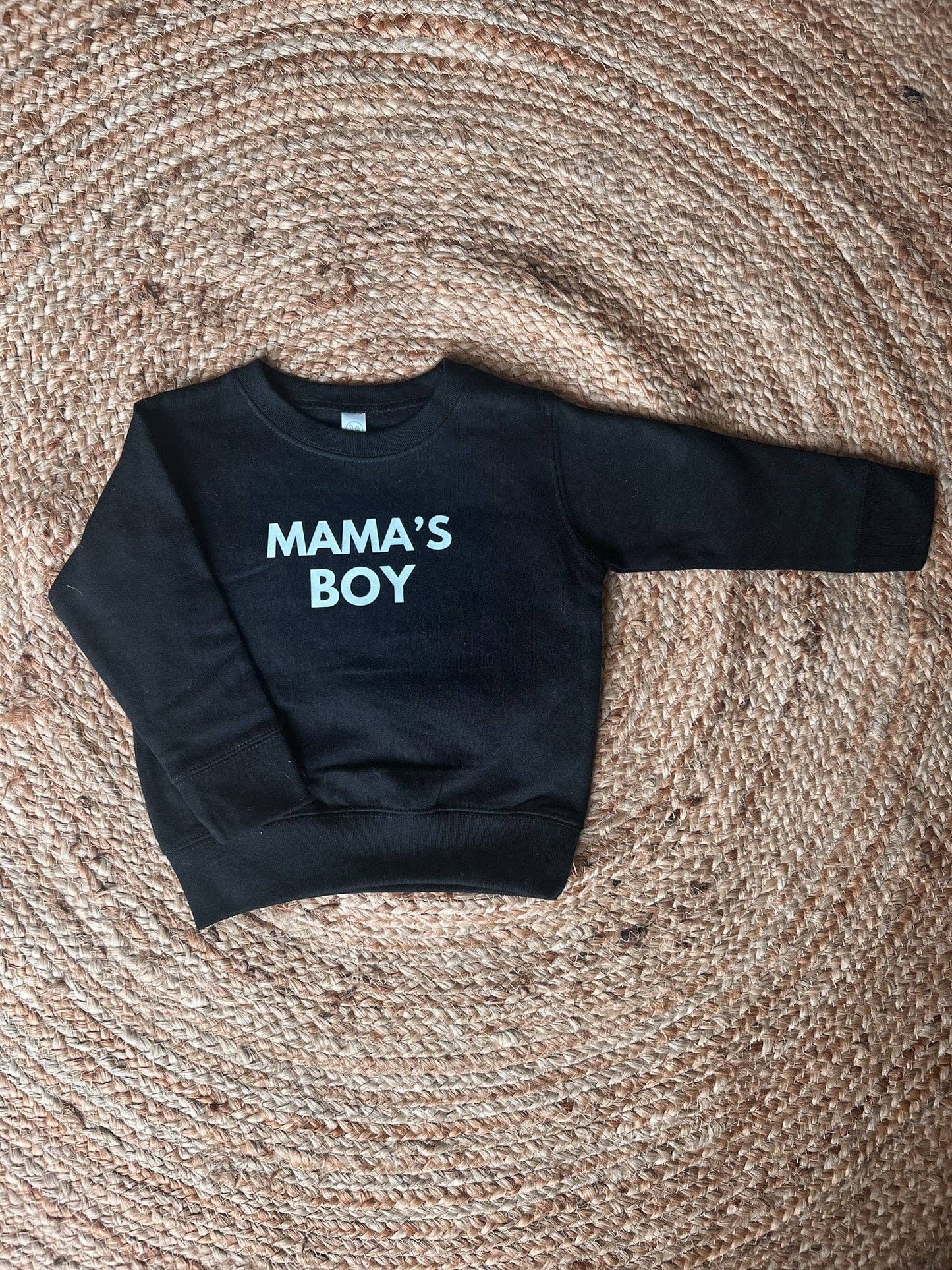 Black sweatshirt with 'MAMA'S BOY' text on a textured surface