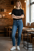 Woman wearing a black t-shirt and blue jeans standing in a cafe.
