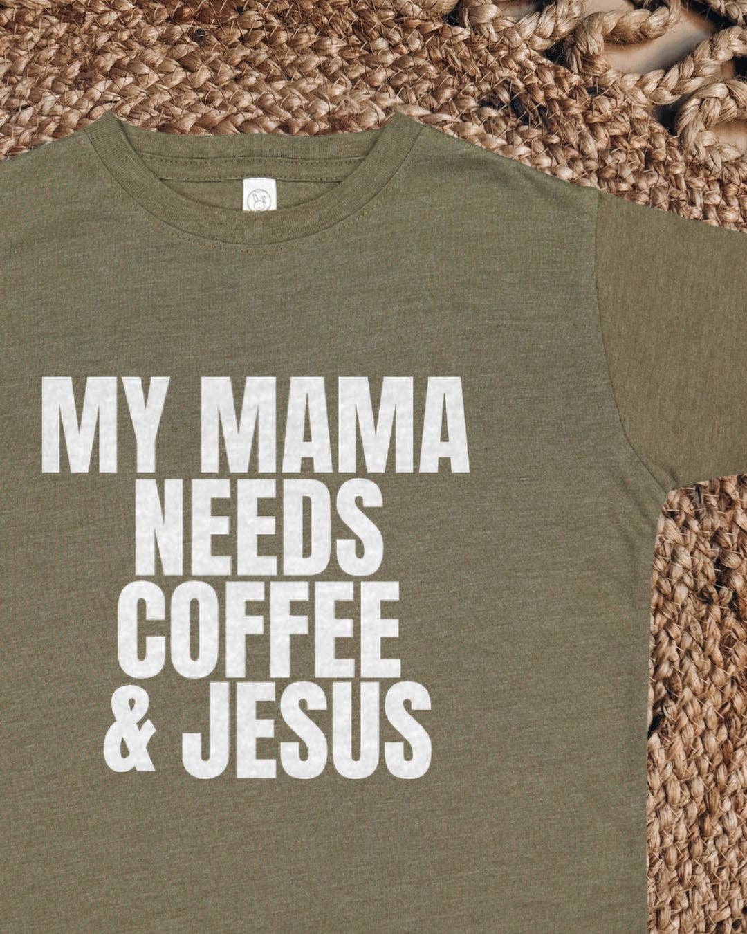 Green t-shirt with 'My Mama Needs Coffee & Jesus' text on a woven surface