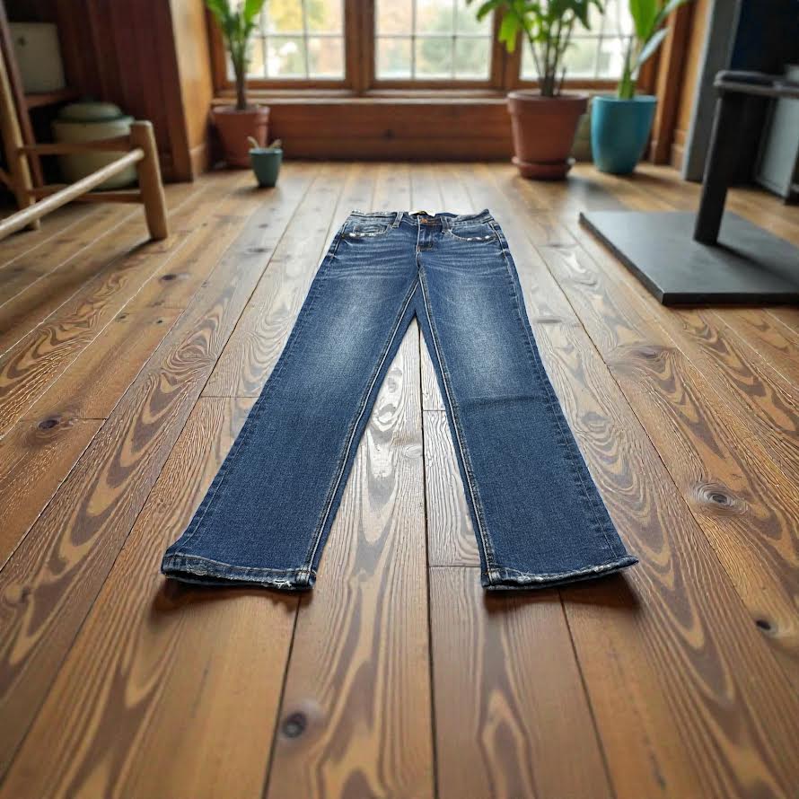 Blue jeans on a wooden floor with plants and furniture in the background