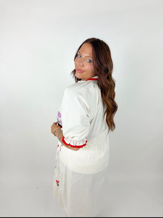 Woman wearing a white outfit with red accents on a plain background